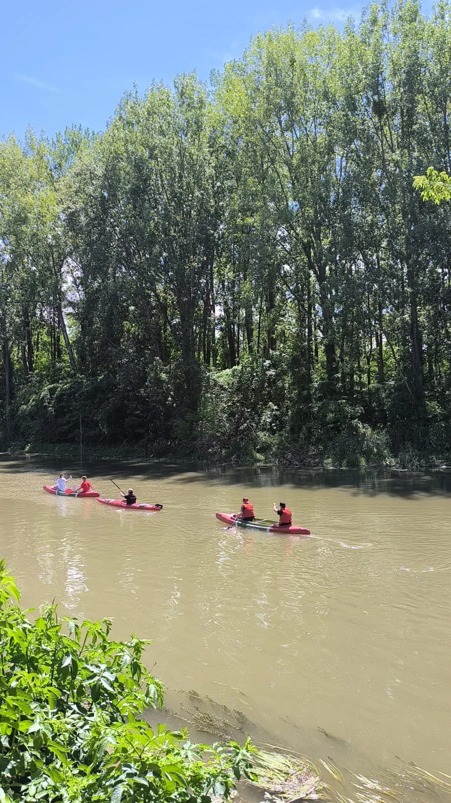 Skupina ľudí na červených kajakoch počas spoločného splavu